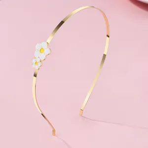 Detail eines goldenen Metall-Haarreifs mit weißen Gänseblümchen auf rosa Hintergrund