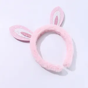 Détail d'un serre-tête oreilles de lapin rose en peluche avec paillettes brillantes