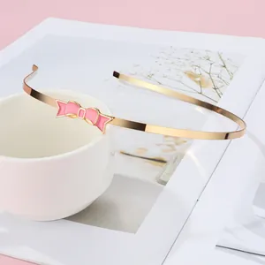 Detailaufnahme eines goldenen Haarreifs mit einer süßen rosa Emaille-Schleife am Tassenrand