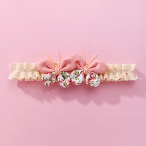 Bandeau bébé avec nœuds floraux roses et dentelle élastique beige sur fond rose