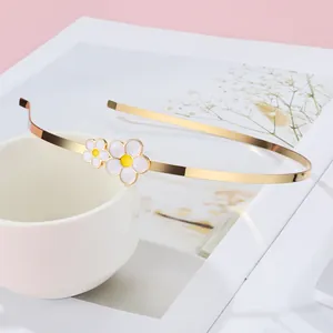 Goldener Metallhaarreif mit zwei weißen Gänseblümchen an einer weißen Tasse drapiert