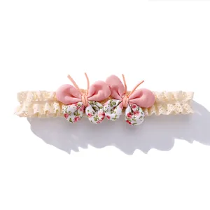 Bandeau bébé en dentelle avec nœuds papillon 3D en tissu fleuri rose sur fond blanc