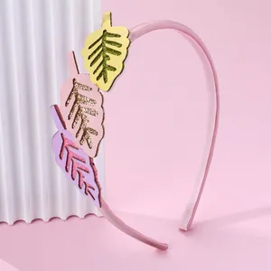 Détail d'un serre-tête rose en tissu avec des motifs de feuilles colorées et paillettes dorées