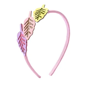 Détail du serre-tête en cuir rose avec feuilles à paillettes pastel et bords dorés