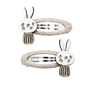 Detail von glitzernden Hasenohr-Haarklammern mit beige gewebtem Stoff und BB-Clips