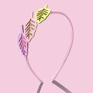 Détail d'un serre-tête rose pour fille avec des feuilles pailletées violettes et jaunes