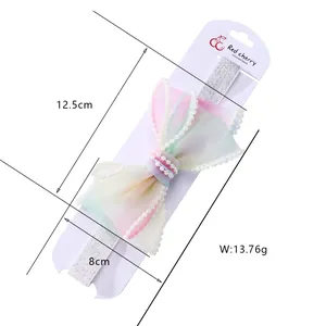 Dettaglio fascia per capelli con fiocco in organza sfumata, perle e misure di 12,5 cm
