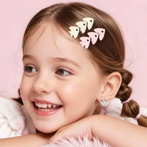 Detail of child model wearing cartoon fish hair clips in matte pink and cream colors