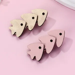 Detail of cute gold and pink fish hair clips with textured leather for children