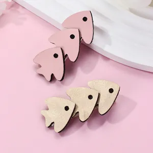 Detail of two layered leather fish hair clips in pink and champagne gold with metal base