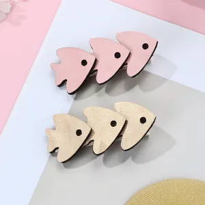 Close-up of pink and gold glittery fish hair clips with detailed faux leather texture