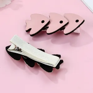 Detail of pink fish hair clips with soft fabric texture and ribbon-wrapped safety clip
