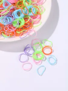 Close-up of colorful high-elasticity hair ties on a white ceramic plate for kids styling
