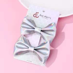 Paio di fermagli per capelli con fiocco argento olografico su carta rosa di supporto