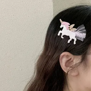 Dettaglio del fermaglio unicorno con tulle rosa e glitter dorati sui capelli