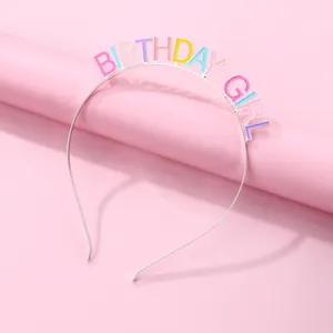 Close-up of rainbow metal Birthday Girl headband with colorful enamel letters on pink background