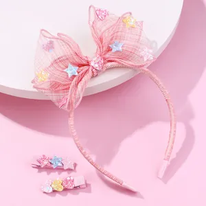 Close-up of pink mesh bow headband and hair clips set with glitter stars and hearts