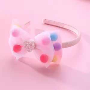 Pink tulle bow headband for kids with colorful pom poms and a glitter heart accent