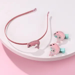 Detail eines rosa Glitzer-Delphin-Haarreifens und zwei Haarspangen für Kinder auf weißem Ständer