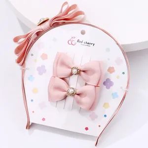 Pink bow headband and hair clips set with pearls and rhinestones on white display card