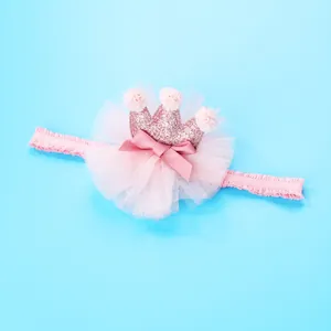 Roze baby haarband met pailletten kroon, pompons en tule strik op blauwe achtergrond