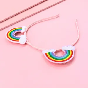 Pink kids headband with embroidered rainbow and cloud patches on a matching pink backdrop