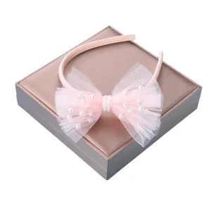 Pink mesh bow headband for girls with faux pearl accents on a display gift box