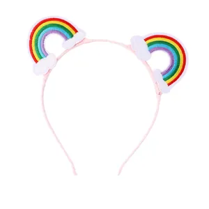 Pink girls headband with embroidered rainbow and cloud patches on white background