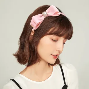 Detail of pink bow headband with faux pearl, rhinestones and golden heart pendant