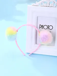 Détail des pompons colorés en fausse fourrure sur un serre-tête rose pour enfants