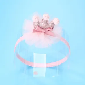 Detail van roze baby haarband met mesh bloem, satijnen strik en lovertjes kroon