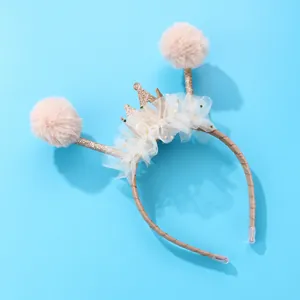 Dettaglio di un cerchietto per bambini con pompon rosa e una corona dorata con glitter