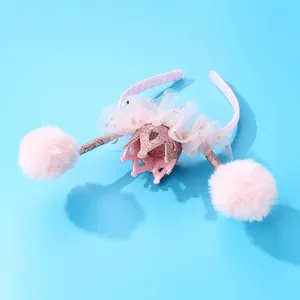 Dettaglio cerchietto rosa con corona scintillante, tulle bianco e pompon di peluche