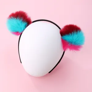 Detail of plush faux fur pom-poms on a non-slip headband with gradient color design