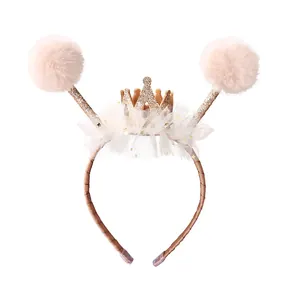 Cerchietto per bambini con corona dorata, pizzo e pompon di peluche su sfondo bianco puro