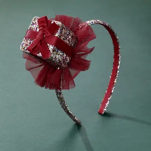 Close-up of a festive headband featuring a red sequin gift box and dark red mesh