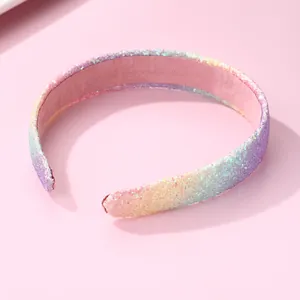 Close-up of glitter rainbow headband with pink velvet lining and sparkling texture