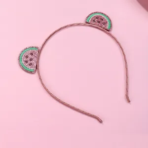 Détail d'un serre-tête en tissu rose avec des tranches de pastèque à paillettes brodées