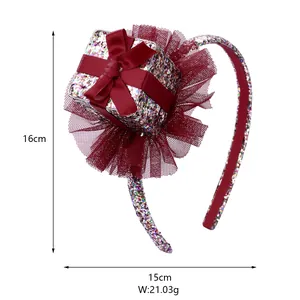 Detail of a festive headband featuring a red gift box with glitter and tulle ruffles