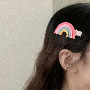 Détail d'une pince à cheveux arc-en-ciel pailletée avec ruban rose sur cheveux