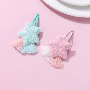 Close-up of star hair clips with glitter sequins and silk tassels in pastel pink and blue