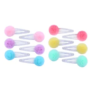 Détail de barrettes à pompon en tulle pailleté aux couleurs pastel de macaron