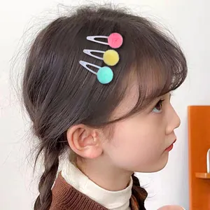 Vue détaillée de trois pinces à cheveux à pompons en tulle coloré sur un enfant