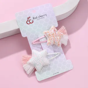 Close-up of star-shaped hair clips with sequins and pastel tassels on pink background