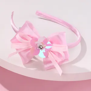 Pink girls headband with double-layered bow and sequin flower detail on white pedestal