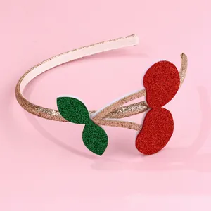 Detail of red cherry headband with gold glitter leaf details on a pink background