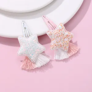 Detail of star-shaped hair clips with sequins and pink tassel fringe on pink background