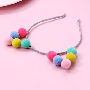 Girl's headband with colorful plush pom poms and cat ears design on pink background