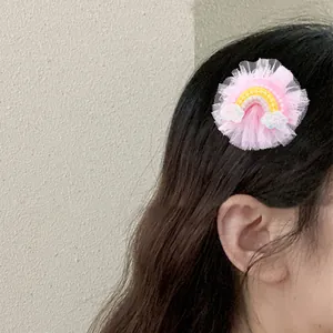 Detail of pink lace mesh hair clip featuring a rainbow and sequined white clouds