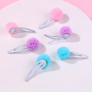 Détail de six barrettes BB à paillettes avec pompons en maille pastel en rose, violet et bleu